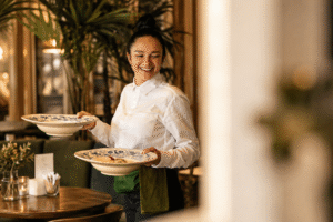 Serveuse brune avec le sourire en train de servir deux assiettes